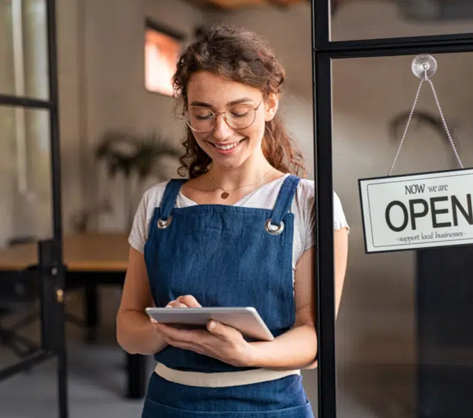 Small business owner using a tablet by an open shop door
